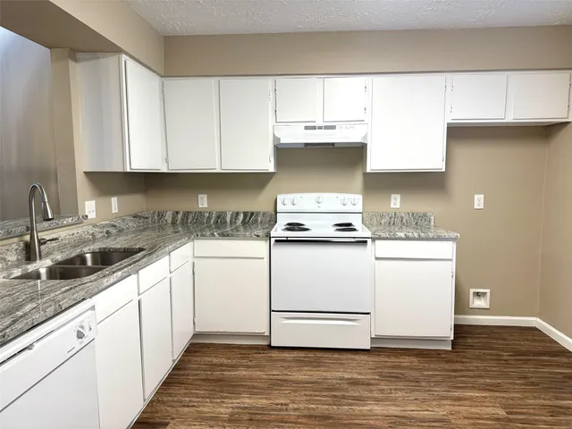a kitchen with granite countertop white cabinets and white appliances