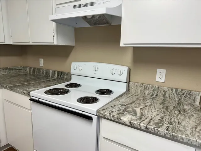 a kitchen with a stove and a white cabinets