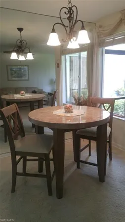a dining room with wooden floor a chandelier a wooden table and chairs