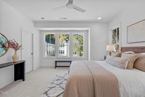 a bedroom with a large bed and a chandelier fan