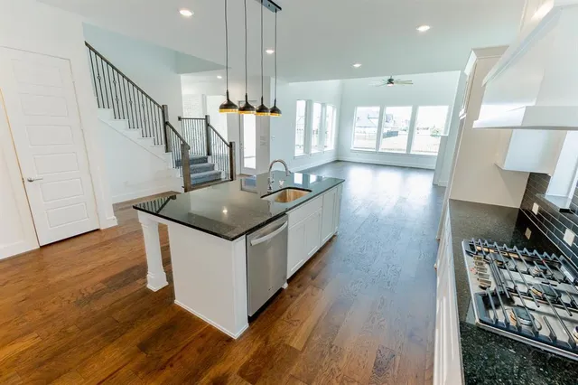 a kitchen with stainless steel appliances granite countertop a stove and a wooden floor