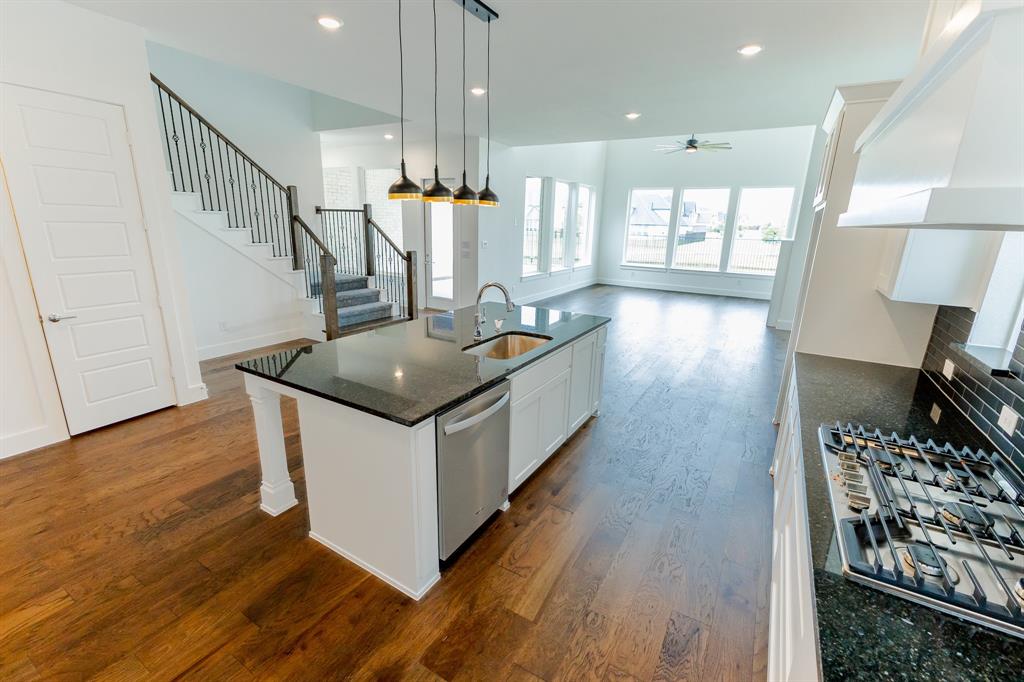3020 Sunfish Street Prosper, TX 75078 - Photo 11 of 34 a kitchen with stainless steel appliances granite countertop a stove and a wooden floor