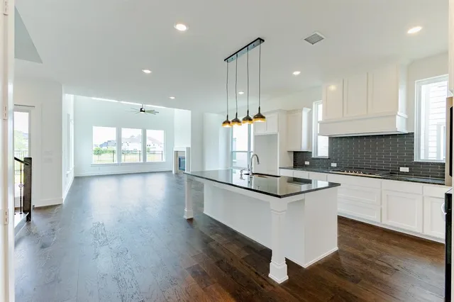 a kitchen with stainless steel appliances granite countertop wooden floors and view living room