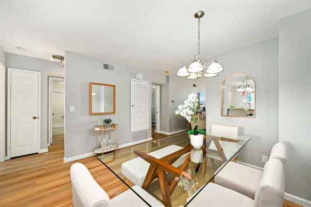a dining room with wooden floor a chandelier a glass table and chairs