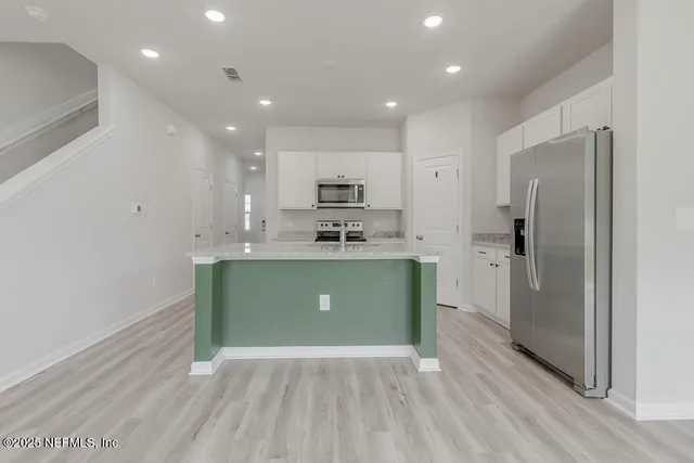 a kitchen with kitchen island a sink stainless steel appliances and cabinets