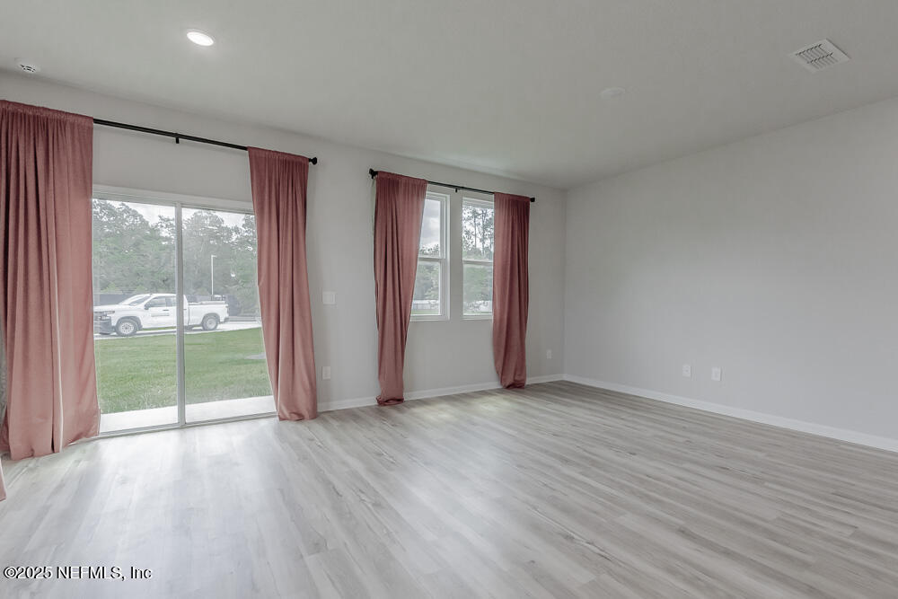 14438 Macadamia Lane Jacksonville, FL 32218 - Photo 12 of 32 an empty room with wooden floor and windows