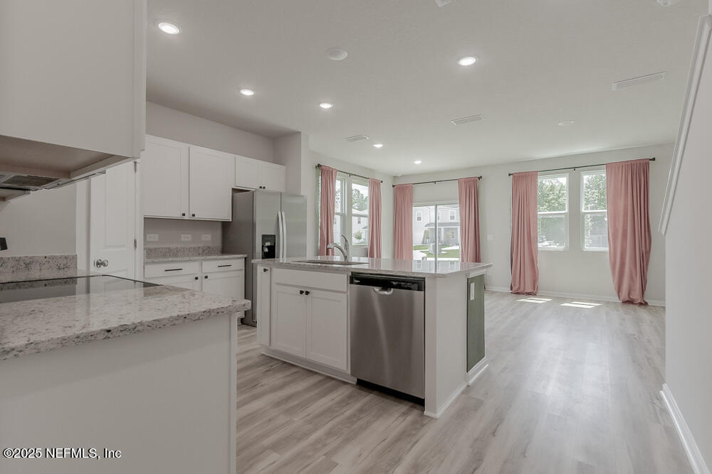 14438 Macadamia Lane Jacksonville, FL 32218 - Photo 2 of 32 a kitchen with stainless steel appliances granite countertop a stove a sink and a refrigerator with wooden floors