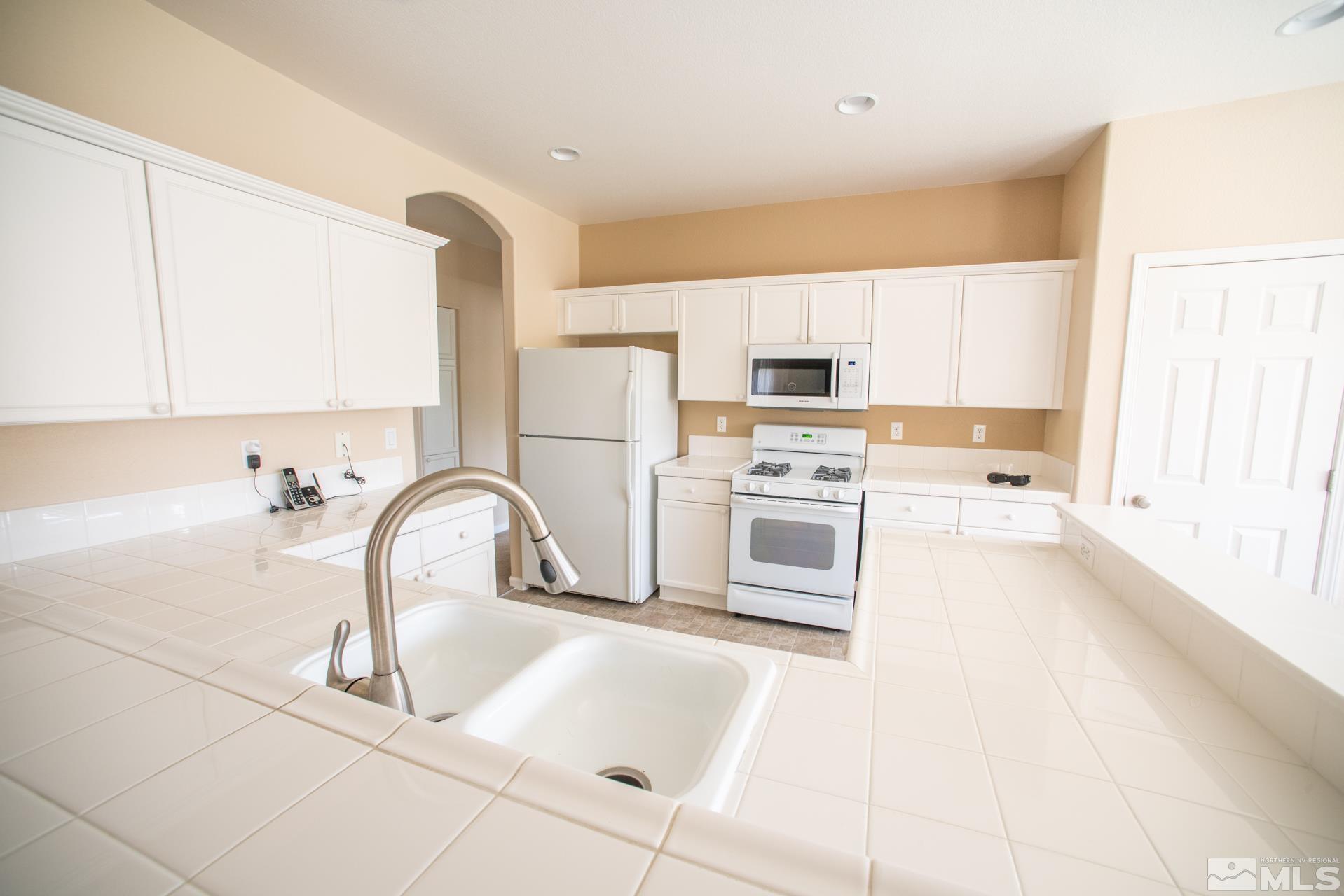 1798 Ornellaia Way Reno, NV 89521 - Photo 8 of 24 a kitchen with stainless steel appliances kitchen island a white counter tops and a stove top oven