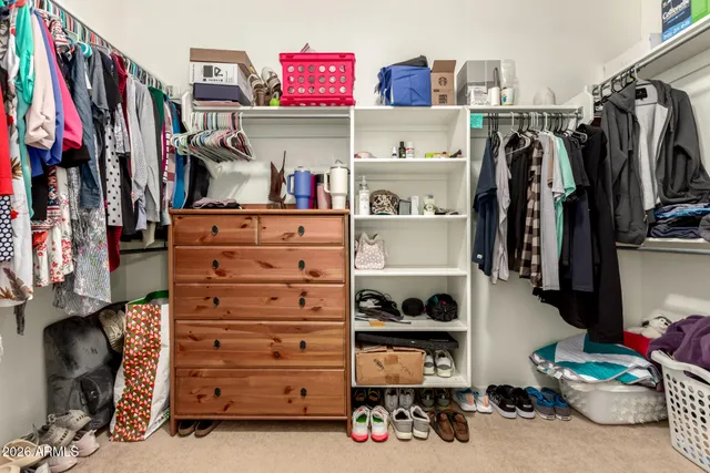 a view of walk in closet with clothes and shoes