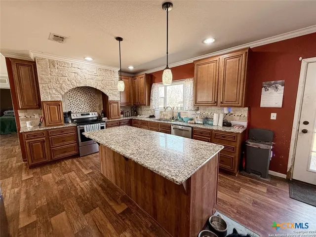 a kitchen with granite countertop a stove a sink dishwasher a refrigerator and wooden floor