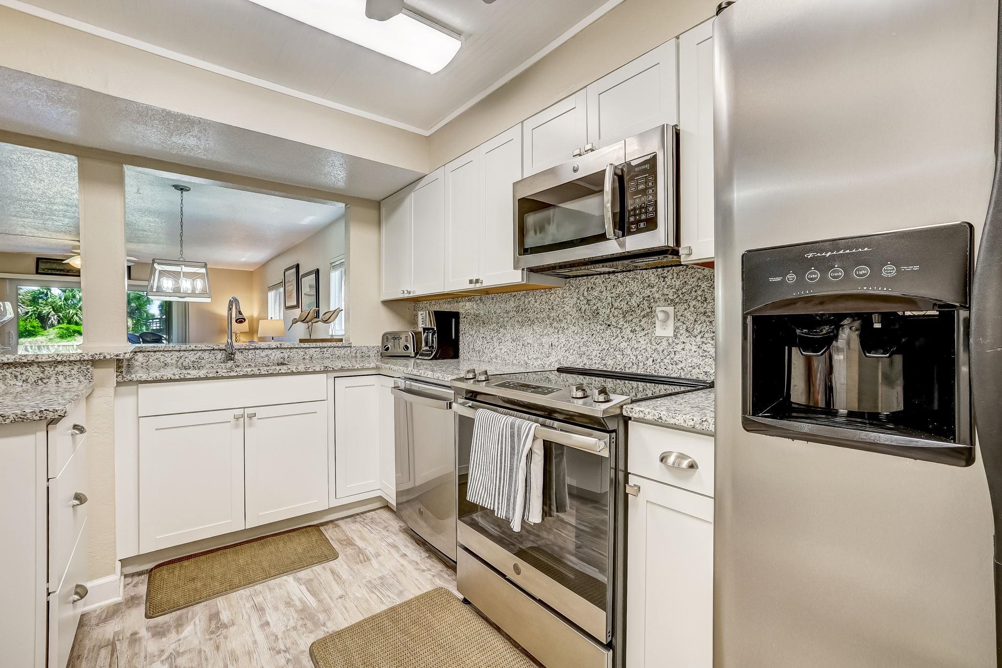 4 Ocean Trace Road, Unit 108 St. Augustine, FL 32080 - Photo 12 of 54 a kitchen with stainless steel appliances granite countertop a stove top oven microwave and cabinets