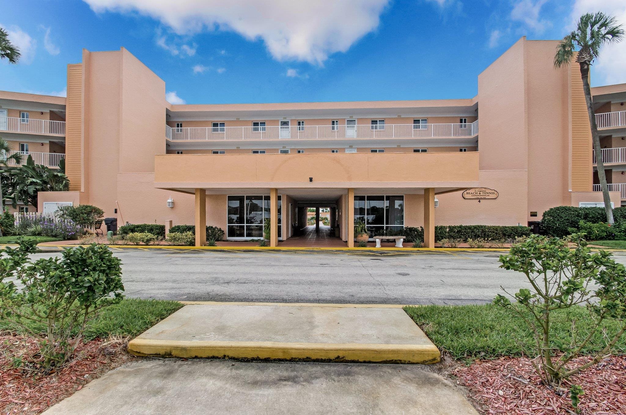 4 Ocean Trace Road, Unit 108 St. Augustine, FL 32080 - Photo 30 of 54 a view of a building with a yard and table and chairs under an umbrella