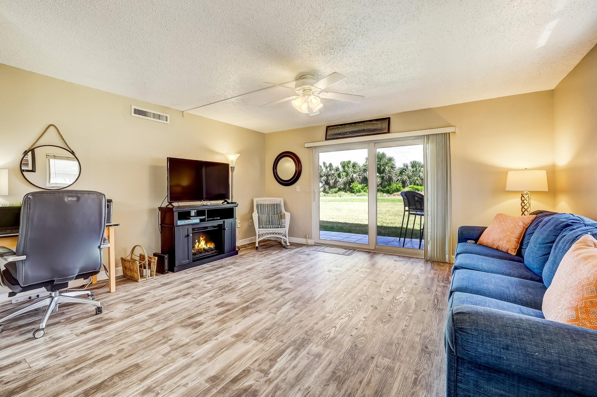 4 Ocean Trace Road, Unit 108 St. Augustine, FL 32080 - Photo 9 of 54 a living room with furniture a flat screen tv and a floor to ceiling window
