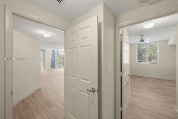 a view of a hallway with wooden floor and a bathroom