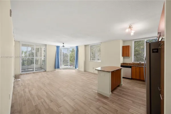 a open kitchen with stainless steel appliances granite countertop a stove a refrigerator a sink dishwasher with wooden cabinets and wooden floor next to a window