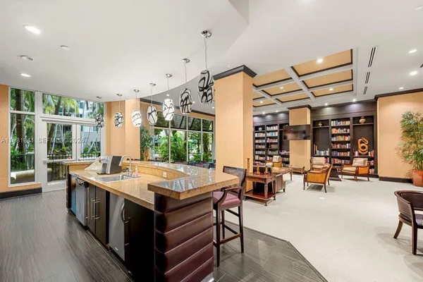 a dining hall with stainless steel appliances granite countertop a lot of chairs and couches with wooden floor