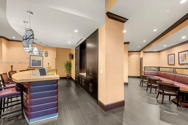 a dining hall with stainless steel appliances kitchen island granite countertop a table chairs and a refrigerator