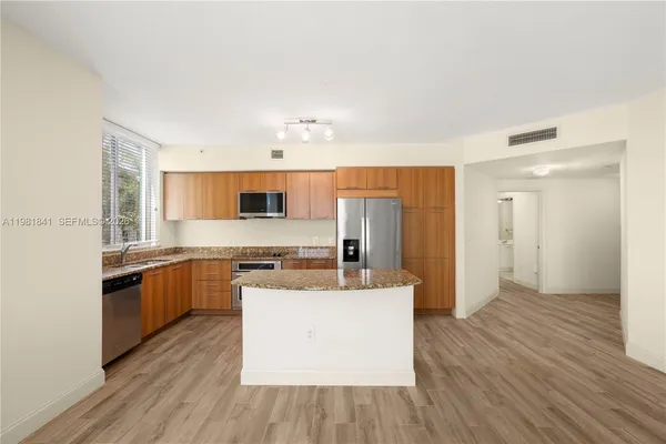 a large kitchen with cabinets wooden floor and stainless steel appliances