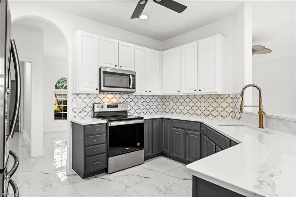 3972 Ruxton Road Naples, FL 34116 - Photo 8 of 41 a kitchen with stainless steel appliances granite countertop a sink stove and microwave