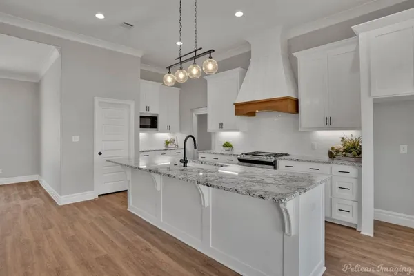 a kitchen with stainless steel appliances granite countertop a sink a stove and a wooden floors