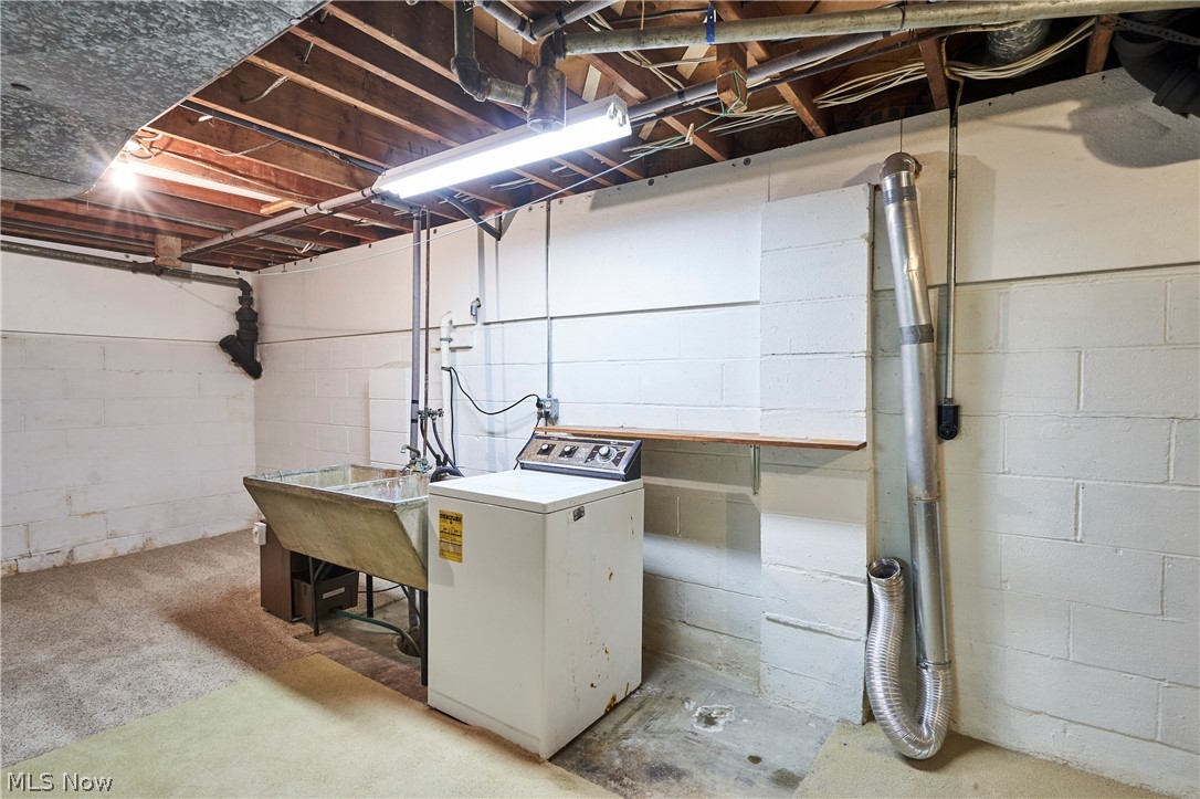 299 West Caston Road New Franklin, OH 44319 - Photo 20 of 23 Utility area featuring a laundry tub, overhead fluorescent lighting, and exposed ceiling joists