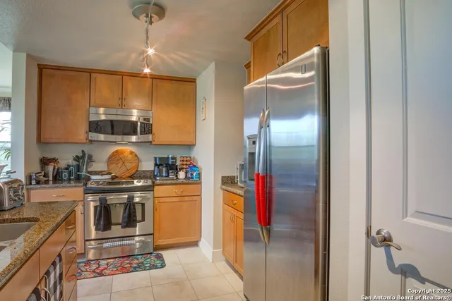 a kitchen with stainless steel appliances granite countertop a refrigerator a stove and a sink