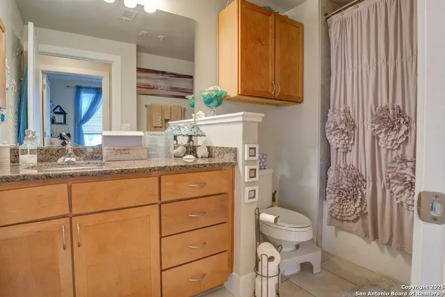 a bathroom with a granite countertop toilet sink and mirror
