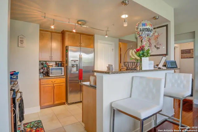 a kitchen with kitchen island granite countertop a refrigerator and a sink