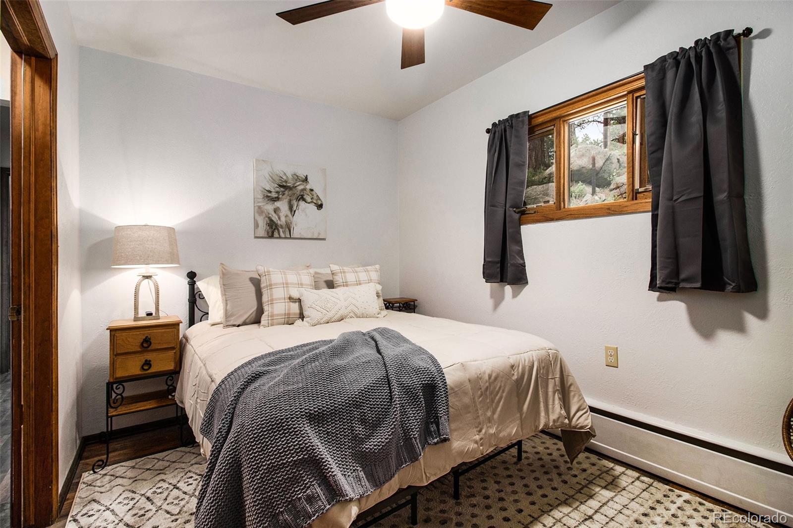 28433 Kinnikinnick Road Evergreen, CO 80439 - Photo 11 of 29 a bedroom with a bed painting on wall and a large window