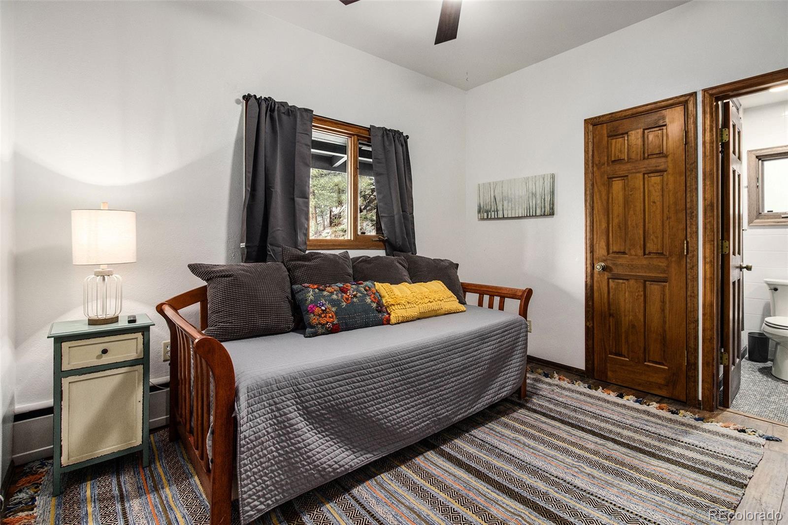 28433 Kinnikinnick Road Evergreen, CO 80439 - Photo 13 of 29 a bedroom with a bed and dresser with mirror