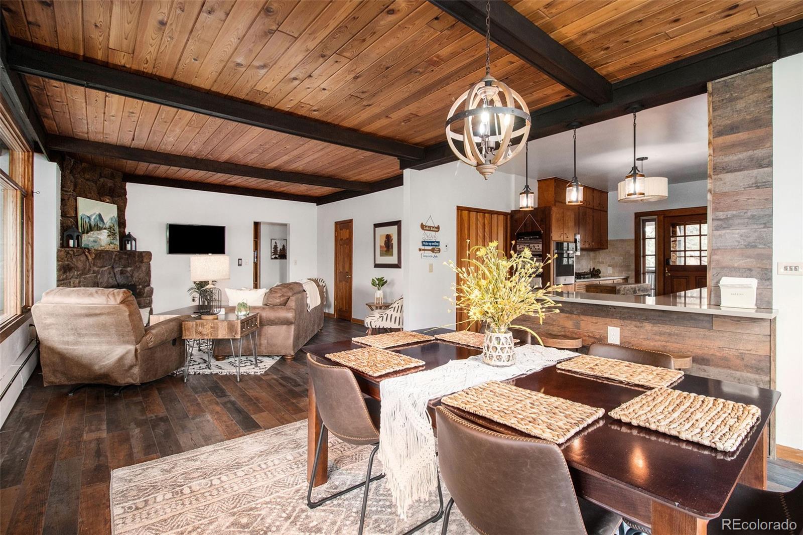 28433 Kinnikinnick Road Evergreen, CO 80439 - Photo 3 of 29 a view of a dining room with furniture a chandelier and wooden floor