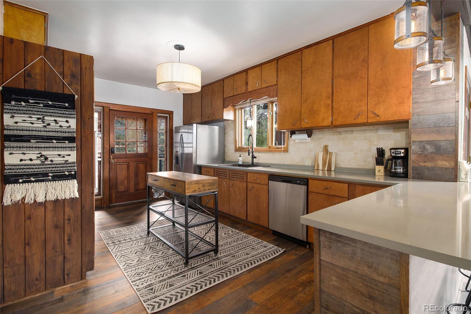 28433 Kinnikinnick Road Evergreen, CO 80439 - Photo 5 of 29 a kitchen with stainless steel appliances wooden cabinets a stove a sink and a microwave
