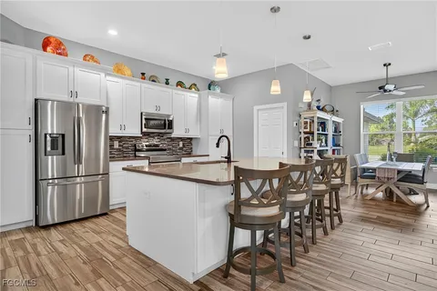 a kitchen with stainless steel appliances a dining table chairs stove refrigerator and cabinets