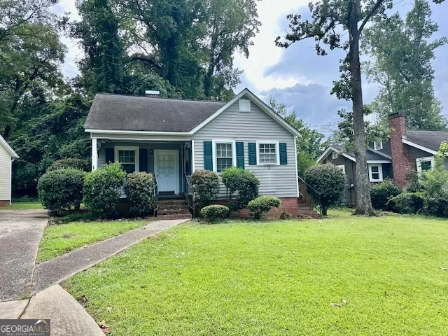a view of a house with a yard and large trees