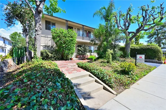 a front view of a house with a yard and potted plants