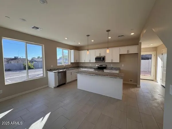 a room with stainless steel appliances kitchen island granite countertop a stove a sink a refrigerator and a cabinets