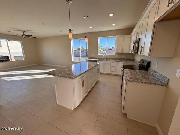 a large kitchen with granite countertop a sink a counter top space appliances and cabinets