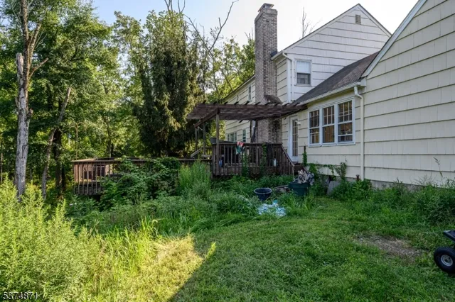a backyard of a house with plants and large tree