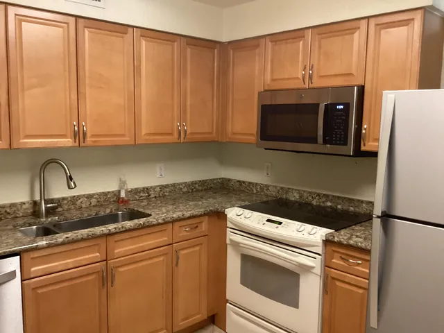 a kitchen with granite countertop cabinets stainless steel appliances and a sink