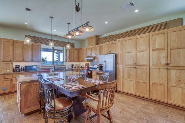 a kitchen with kitchen island a dining table chairs stainless steel appliances and cabinets