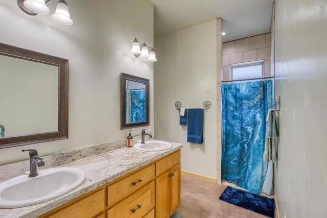 a bathroom with a granite countertop sink a mirror and a shower