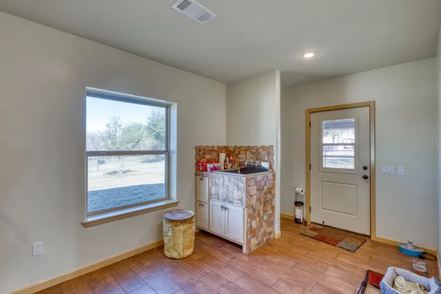 a view of an empty room with a window and wooden floor