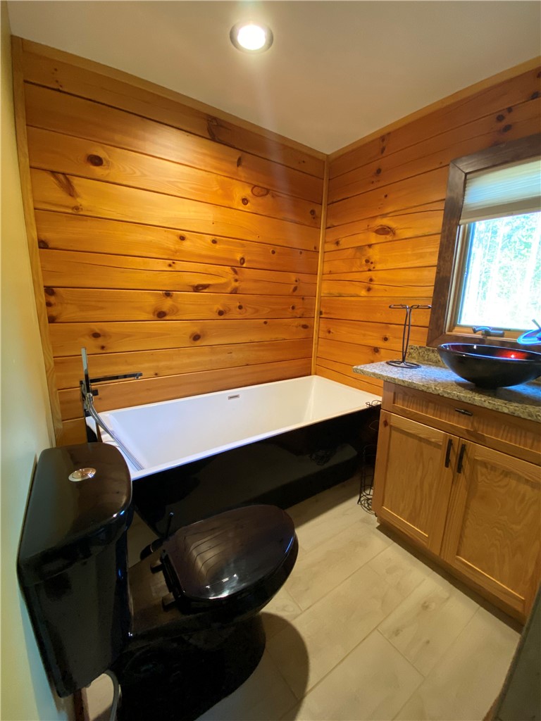 128 McAlister Road West Union, SC 29696 - Photo 11 of 40 Natural wood paneling and sleek fixtures create a unique and cozy bathing sanctuary.