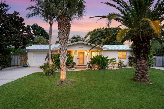 a front view of a house with a garden and trees