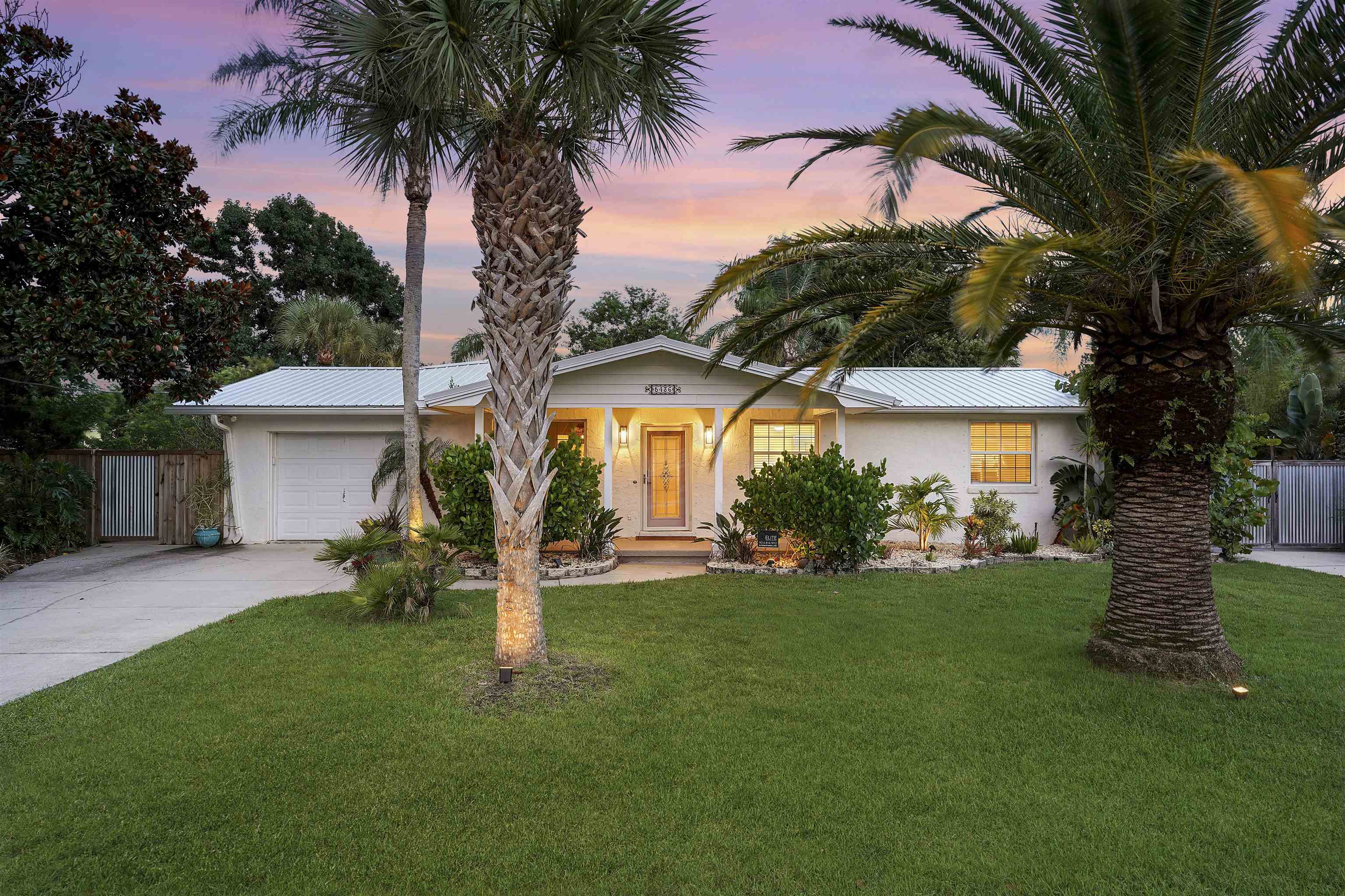 a front view of a house with a garden and trees