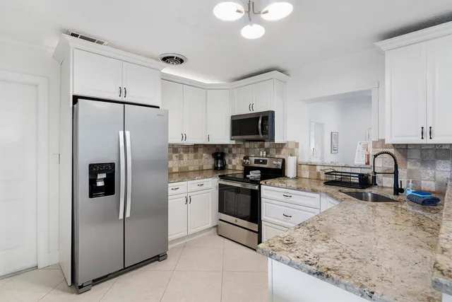 a kitchen with stainless steel appliances granite countertop a refrigerator a stove top oven a sink and dishwasher