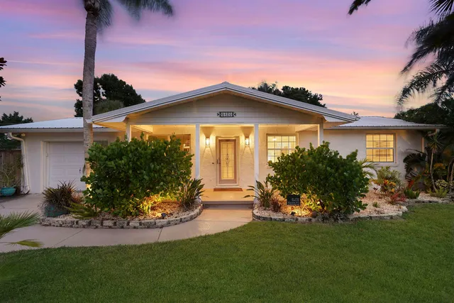 a front view of a house with a garden and plants