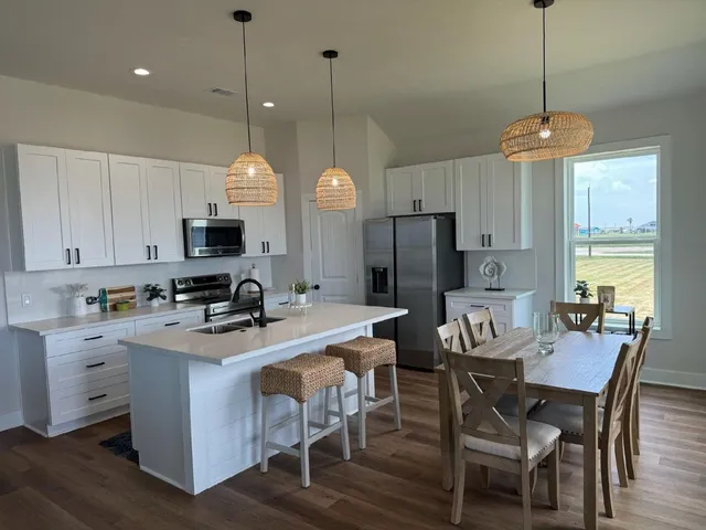 a kitchen that has a table chairs refrigerator and microwave