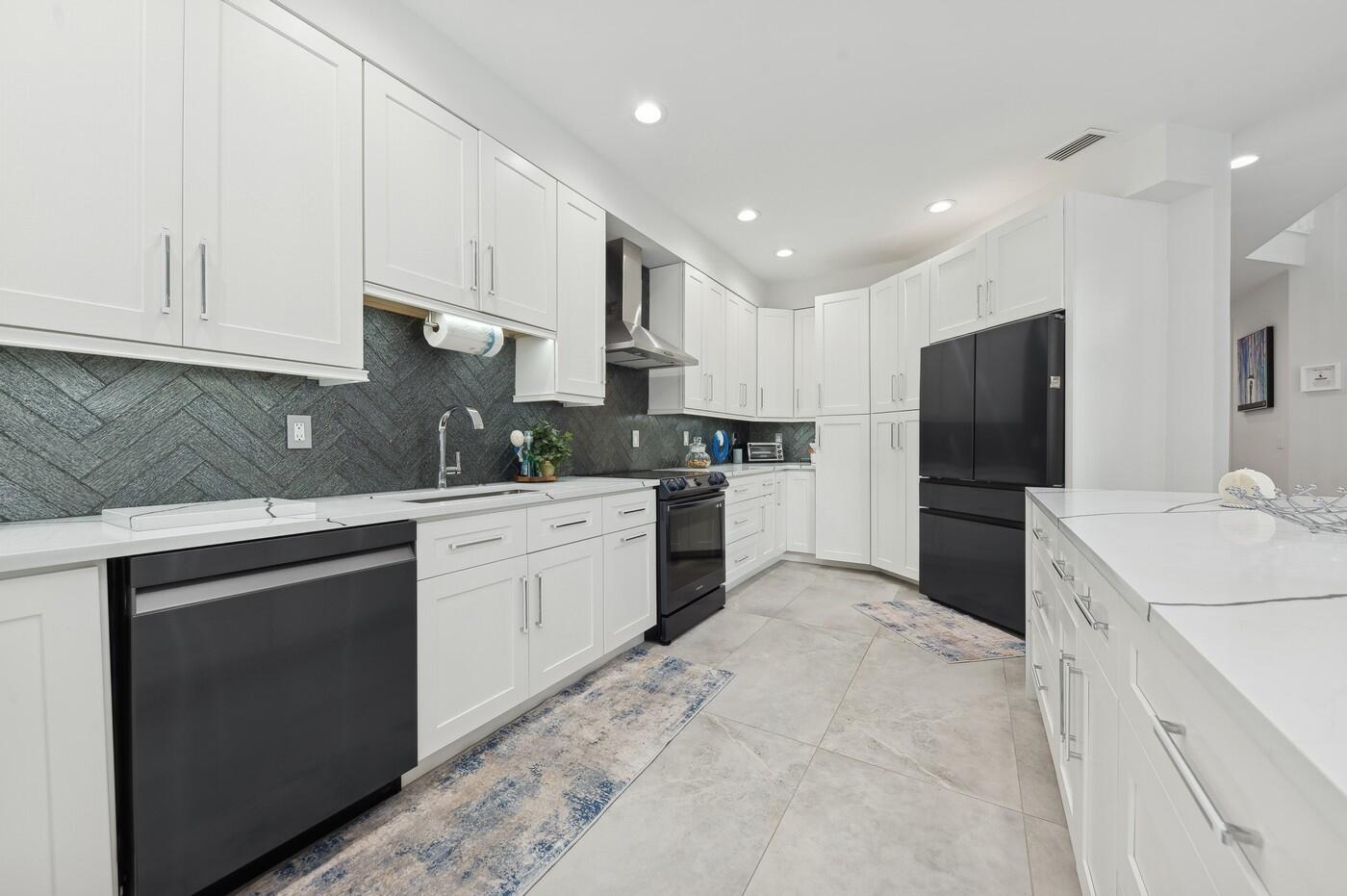 2558 Northwest 52nd Street Boca Raton, FL 33496 - Photo 11 of 27 a kitchen with white cabinets and stainless steel appliances