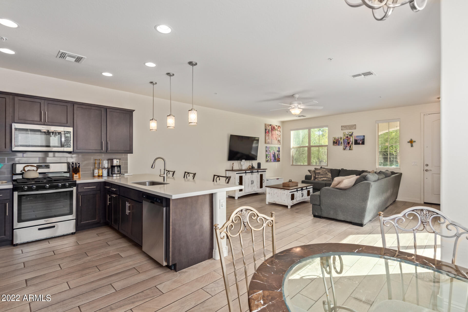 2345 North Alsap Road Buckeye, AZ 85396 - Photo 12 of 50 a kitchen with stainless steel appliances granite countertop a stove top oven a sink dishwasher a dining table and chairs with wooden floor
